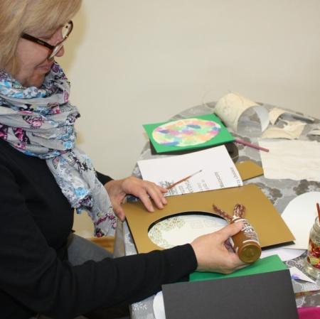 Uczestniczka warsztatów wykonuje kartkę na okazję świąt wielkanocnych.