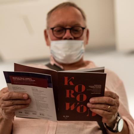 Mężczyzna trzymający w rękach otwartą broszurę do wystawy