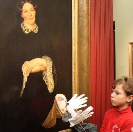 Uczestniczka warsztatów z kukiełką przed obrazem "Portret matki" Henryka Rodakowskiego.