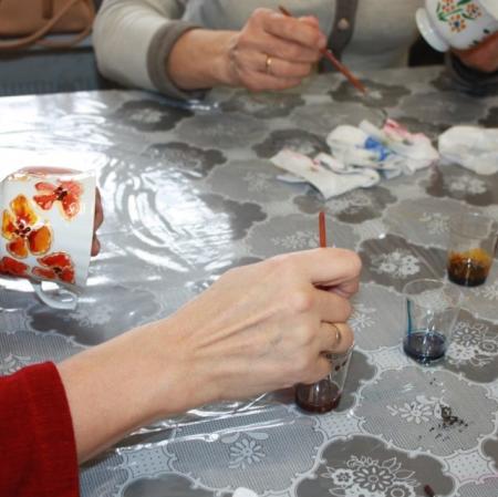 Uczestniczka warsztatów malująca filiżankę - zbliżenie.