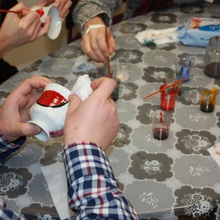 Uczestniczka warsztatów malująca filiżankę - zbliżenie.