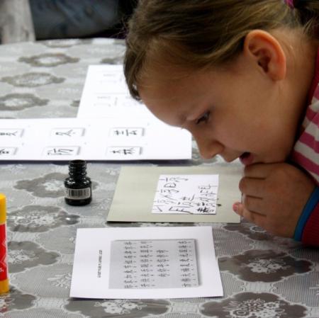 Uczestniczka warsztatów przygląda się literom japońskiego alfabetu.