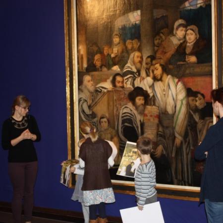 Uczestnicy warsztatów prezentują swoje prace pod obrazem "Żydzi modlący się w synagodze".