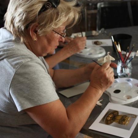 Uczestniczka warsztatów dekoruje filiżankę w stylu empirowym