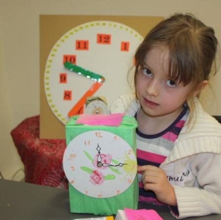 Uczestniczka warsztatów prezentuje wykonany przez siebie zegar.