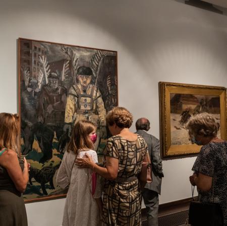 Kilka osób oglądających obrazy na wystawie