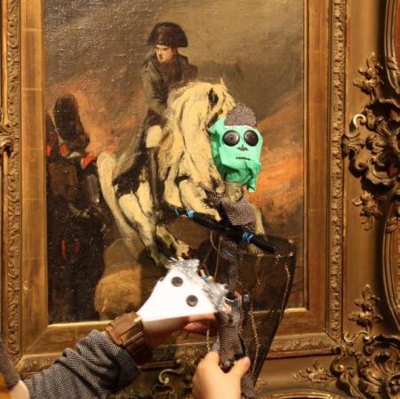 Prezentacja kukiełki przedstawiającej Napoleona przed obrazem Piotra Michałowskiego "Napoleon na koniu".