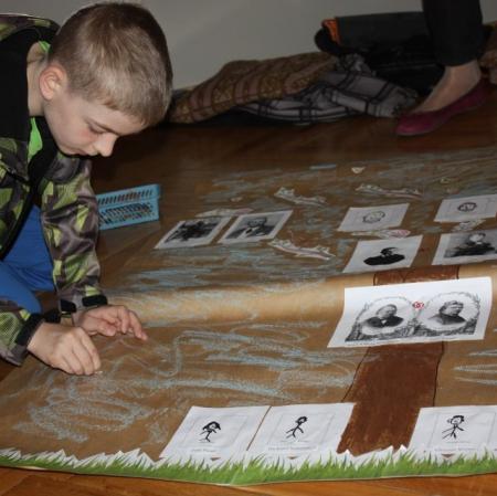 Twórcze dekorowanie drzewa genealogicznego rodziny Herbstów i Scheiblerów na wystawie "Herbstowie. Historie niedokończone" przez młodszego uczestnika warsztatów.