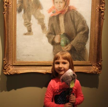 Dziewczynka z kukiełką przed obrazem Teodora Axentowicza.