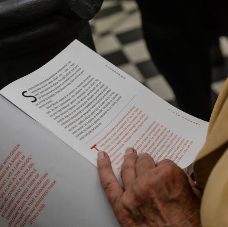 Zbliżenie na dłoń przewracającą strony broszury do wystawy.