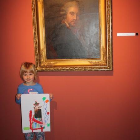 Uczestniczka warsztatu prezentuje swoją pracę pod obrazem "Autoportret" Marcello Bacciarellego.