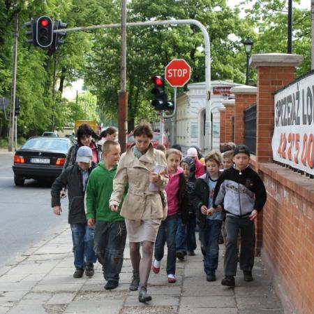 Uczestnicy  warsztatów idą wzdłuż ogrodzenia budynku dawnej przędzalni.