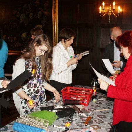 Uczestnicy karnawału wykonują swoje własne maski za pomocą przygotowanych materiałów na sali balowej w Pałacu Herbsta.