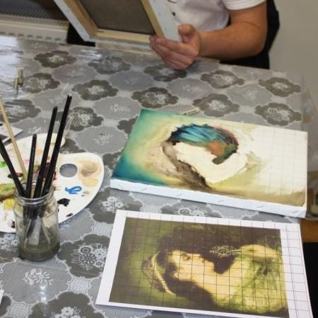 Widok na stół - reprodukcja obrazu oraz jego kopia we wstępnej fazie; malarska paleta, pędzle