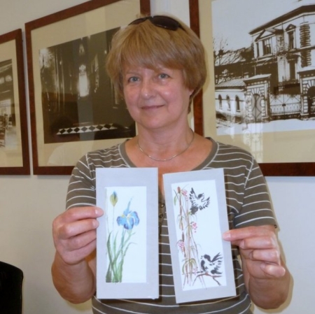 Uczestniczka warsztatów prezentuje swoje prace wykonane  farbami do malowania na jedwabiu.