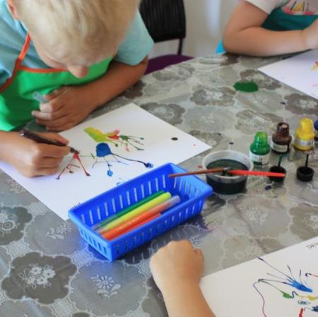 Uczestnicy warsztatów Pałacowa menażeria w sali edukacyjnej tworzą zwierzaki-cudaki za pomocą kolorowego tuszu i flamastrów.