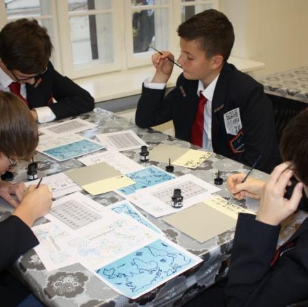 Uczestnicy warsztatów kaligrafują litery japońskiego alfabetu.