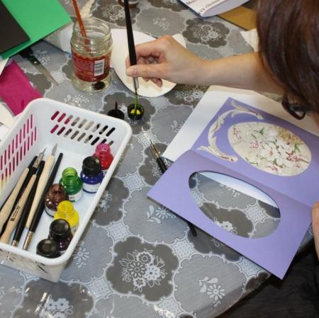 Uczestniczka warsztatów wykonuje kartkę na okazję świąt wielkanocnych.