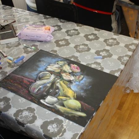 Uczestniczka warsztatów wykonująca martwą naturę pastelami.
