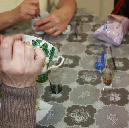 Uczestniczka warsztatów malująca filiżankę - zbliżenie.