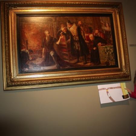 Uczestniczka warsztatu prezentuje swoją pracę pod obrazem "Alchemik Sędziwój i król Zygmunt III" Jana Matejki.