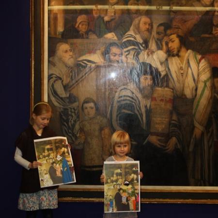 Uczestnicy warsztatów prezentują swoje prace pod obrazem "Żydzi modlący się w synagodze".