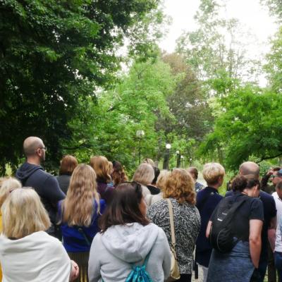 Zdjęcie przedstawia liczną grupę dorosłych wśród zielonych drzew.