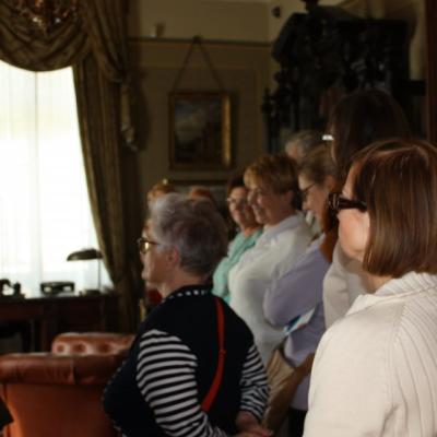 zdjęcie przedstawia kilka osób stojących plecmi do nas we wnętrzu. Wszyscy są zwróceni w jednym kierunku.