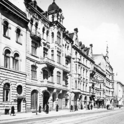 Czarno-białe zdjęcie ulicy wzdłuż niej rząd kamienic