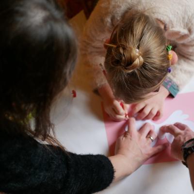 zdjęcie z góry przedstawia zbliżenie na kobietę i dziecko pochylone nad kolorowymi kartkami