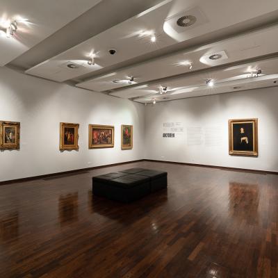 Zdjęcie przedstawia wielką salę, na ścianach której wiszą obrazy