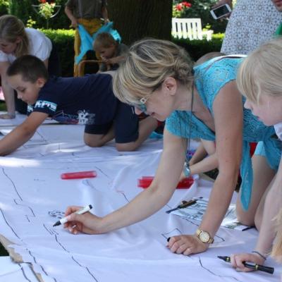 Uczestnicy warsztatów wykonują plan Księżego Młyna na płótnie rozłożonym w przypałacowym ogrodzie.