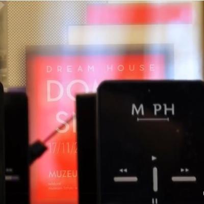 Czarne urządzenia audioprzewodników  na tle plakatu wystawy "Dom ze snów"