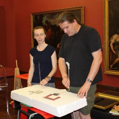 Uczestnik warsztatu "Pałac Herbsta w kilku odsłonach" odwzorowujący jeden z obrazów za pomocą papierowych kukiełek.